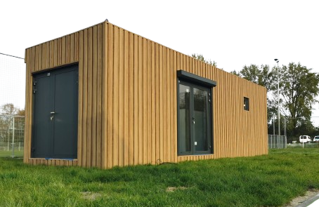 Moderne pavillon med træbeklædning, store vinduer og et sort tag, placeret som en separat bygning.